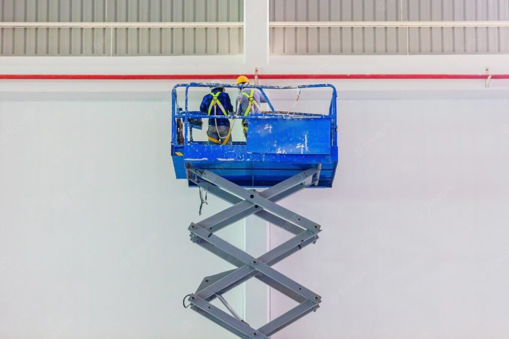 Blue scissor lift with two construction workers wearing hard hats