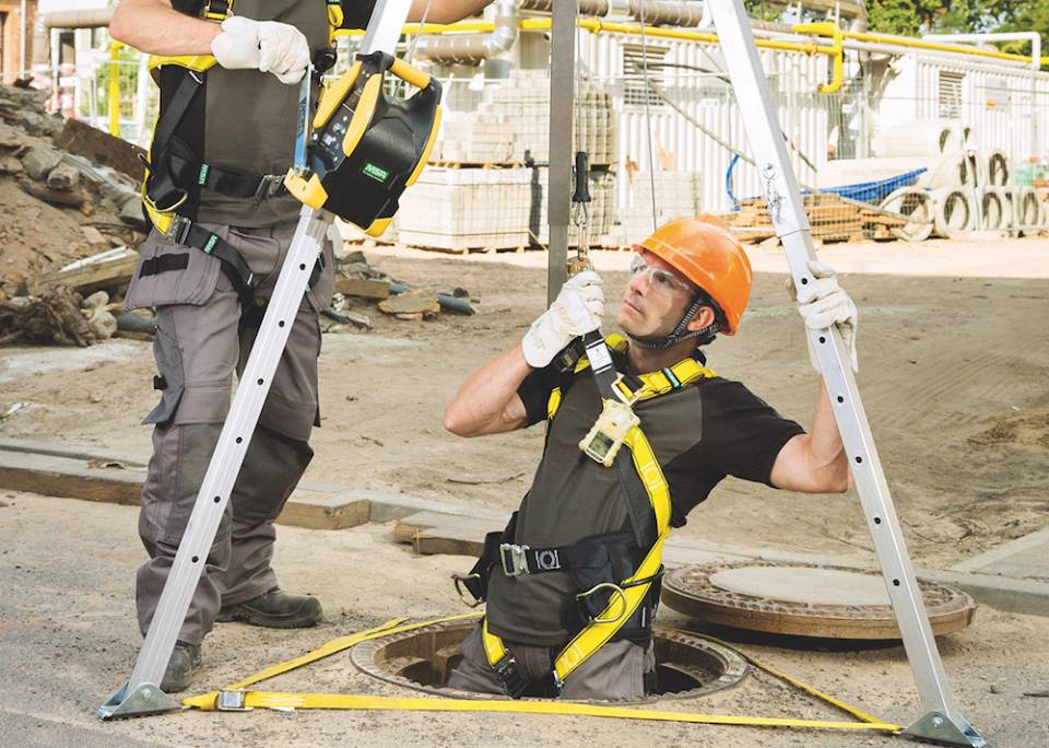 Man with hardhat being lowered into a confined space